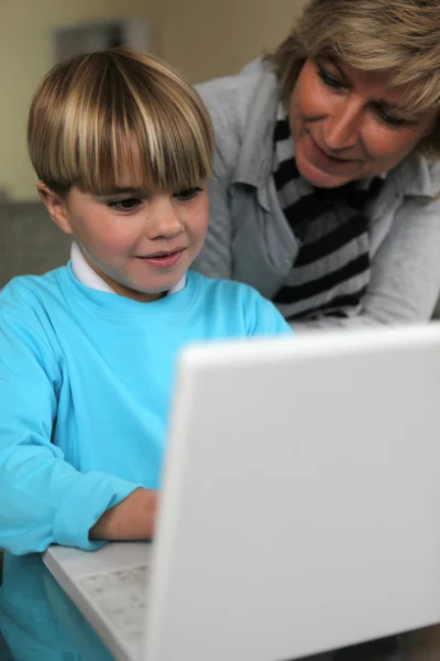 母亲和儿子一起在沙发上使用便携式计算机 — 图库照片