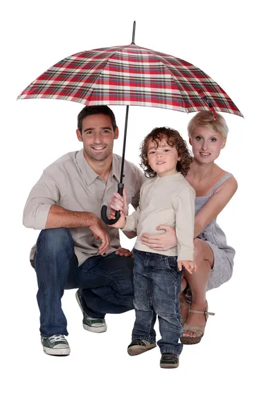 Young family sheltering under an umbrella — Stock Photo, Image