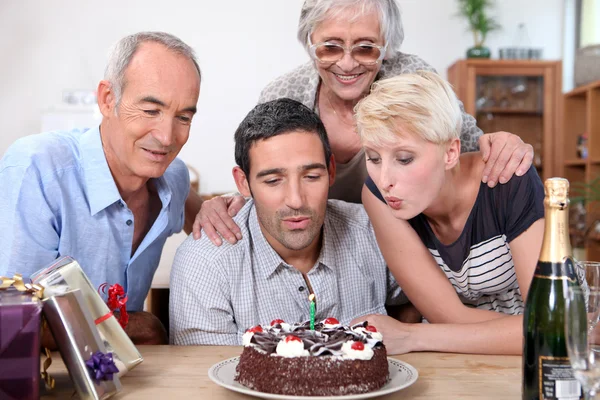 Frau bläst Geburtstagskerzen in Familie — Stockfoto