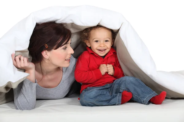 Mãe e filho se escondendo sob cobertor — Fotografia de Stock