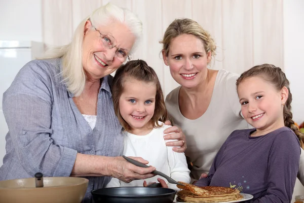 Grootmoeder maakt crêpes omringd door dochter en kleinkinderen — Stockfoto
