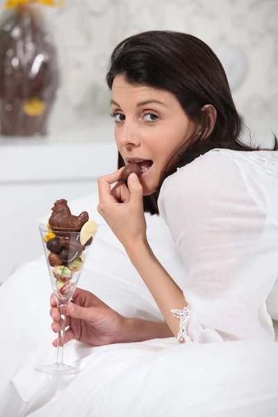 Yatakta çikolata yiyen kadın — Stok fotoğraf