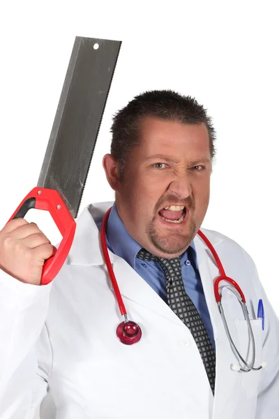 Médico irritado segurando uma serra — Fotografia de Stock
