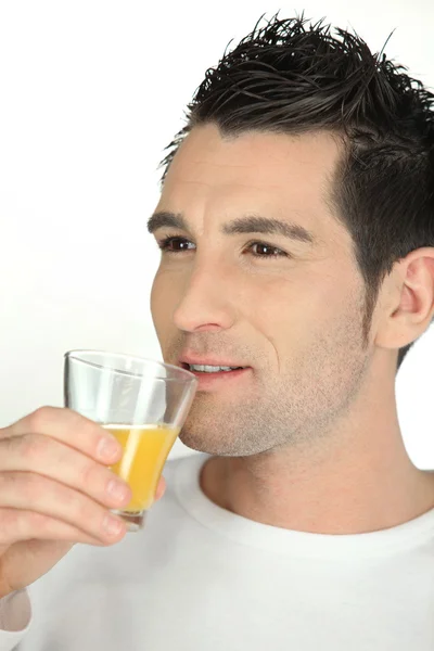 Человек пьет стакан апельсинового сока — стоковое фото