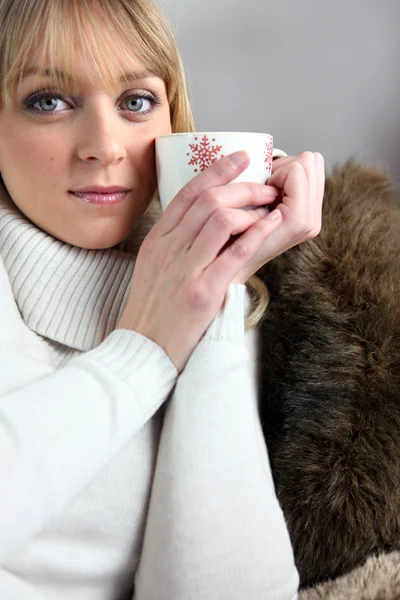 Mujer rubia sentada en el sofá con una taza de café — Foto de Stock