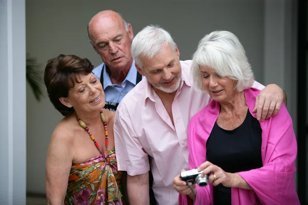 Deux couples âgés regardant des photos sur un appareil photo numérique — Photo
