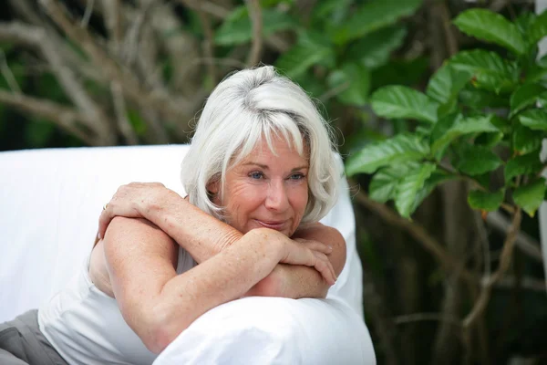 Idős hölgy a kertben kanapé — Stock Fotó