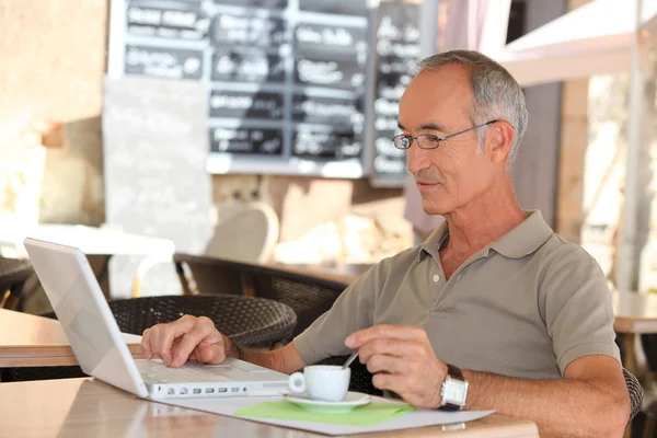 Starszy człowiek, picia kawy i sprawdzenie jego e-maile — Zdjęcie stockowe