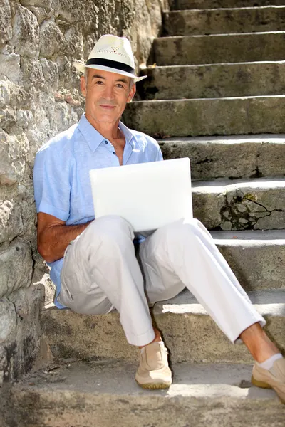 Пенсионер отдыхает на свежем воздухе с ноутбуком — стоковое фото