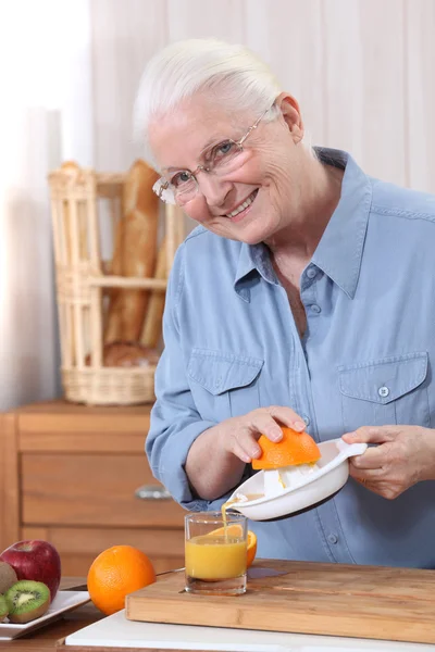 Ηλικιωμένη γυναίκα ρίχνει φρέσκο χυμό πορτοκάλι — Φωτογραφία Αρχείου