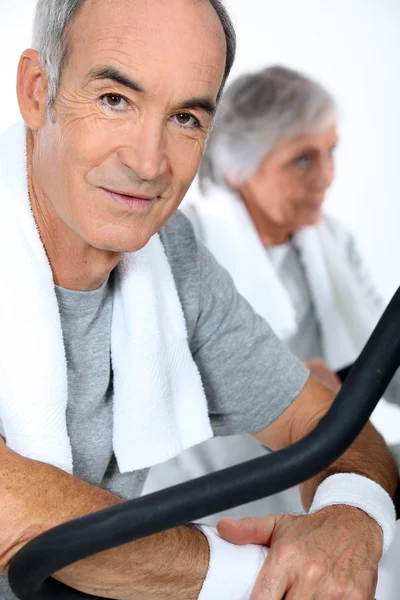 Middle-aged couple cycling at the gym — Stock Photo, Image