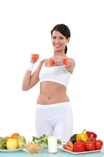 Mujer haciendo ejercicio delante de las verduras — Foto de Stock