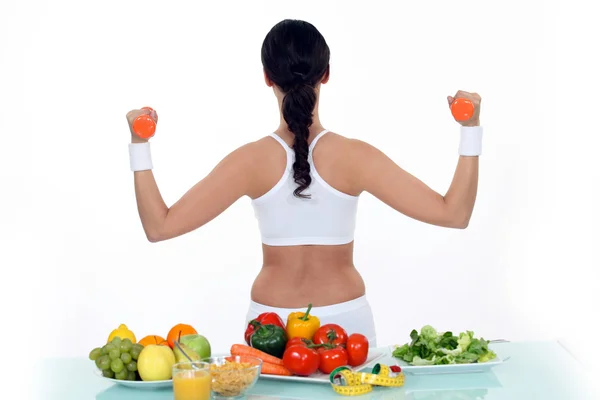 Frau stemmt Gewichte mit dem Rücken zum Gemüse — Stockfoto