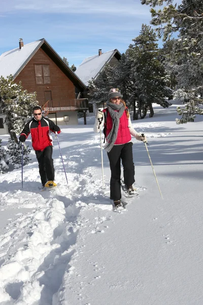 Paar skiën door hun chalet — Stockfoto