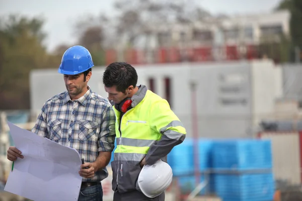 Zwei Bauarbeiter halten an den Plänen fest — Stockfoto