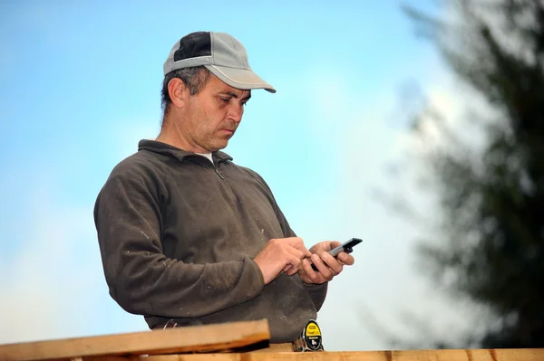 Carpenter enviando mensagem de texto enquanto trabalhava ao ar livre — Fotografia de Stock