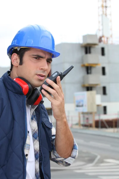 Foreman on construction site giving orders via radio — Stock Photo, Image