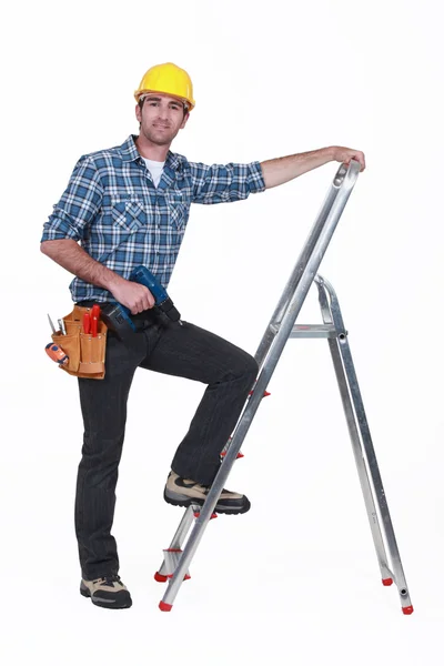 はしごを登るドリルを持つ男 ロイヤリティフリーのストック画像