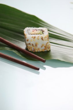 Single sushi resting on green leaf clipart