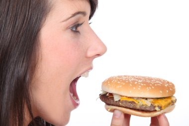 Brunette girl eating hamburger, profile-view clipart