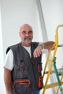 Bald handyman posing by ladder clipart