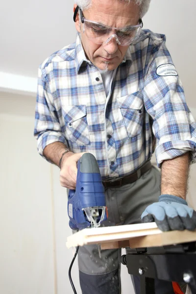 Muž piercing díru skrz dřevěnou prkennou — Stock fotografie