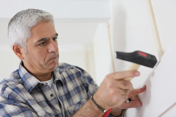 Homem de cabelos grisalhos reparando casa — Fotografia de Stock