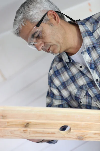Carpintero inspeccionando madera — Foto de Stock