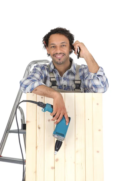 Carpenter interrupting work to take call — Stock Photo, Image