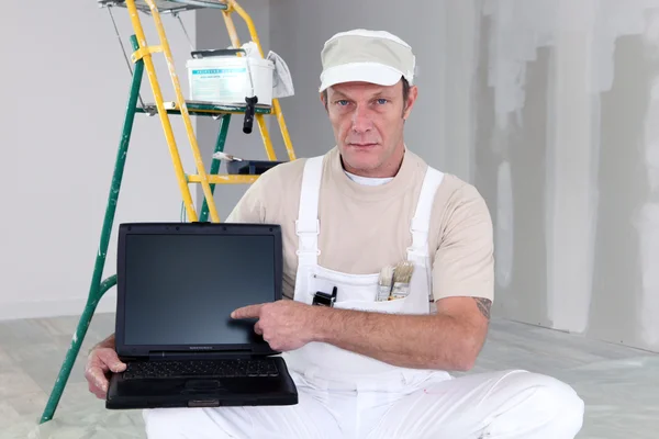 Pintor apontando para seu laptop — Fotografia de Stock