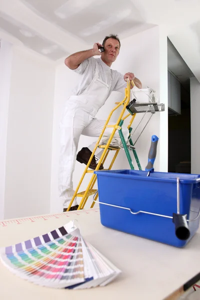 Pintor en el trabajo en escalera haciendo una llamada — Foto de Stock