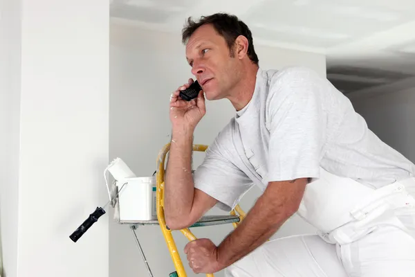 stock image Man taking a phone call whilst painting