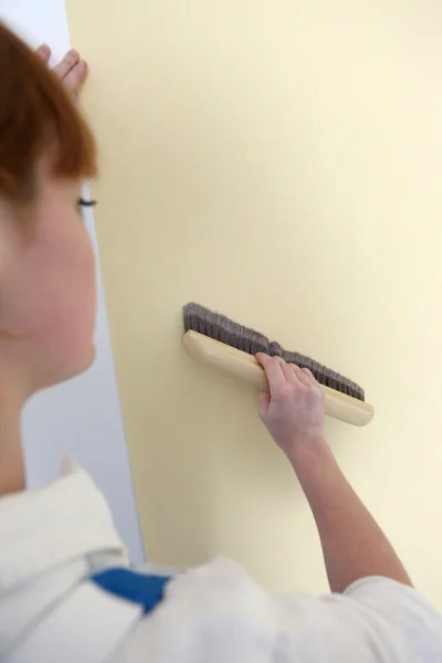 Woman smoothing down wallpaper — Zdjęcie stockowe