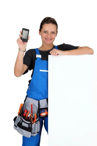 Woman with blank board, toolbelt and cellphone — Stock Photo, Image