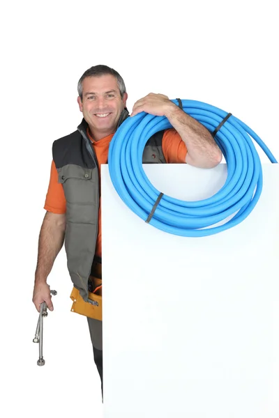 Smiling man with blank board and blue tube — Stock Photo, Image
