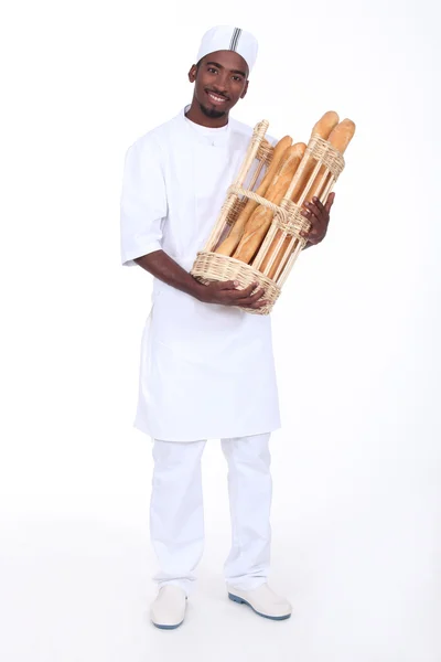 Boulanger avec un panier de baguettes — Photo