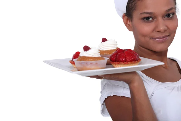 Bakery worker holding plate of fruit tarts — Stock Photo, Image