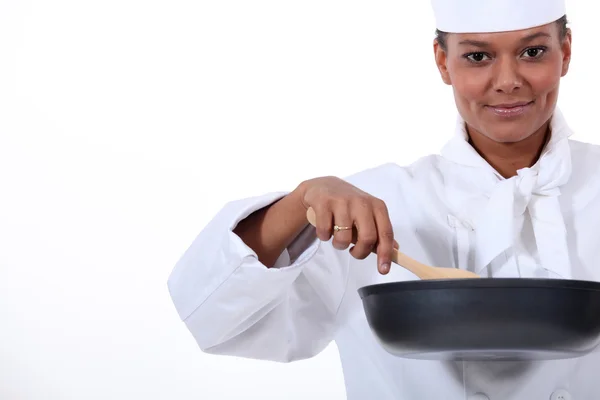 Yüksek önlü arkalı tava ve bir tahta kaşık ile kadın aşçı — Stok fotoğraf