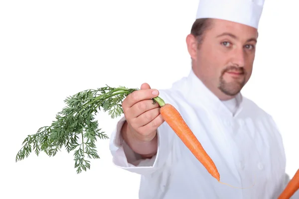 Chef in uniform offering forth a carrot — Stock Photo, Image