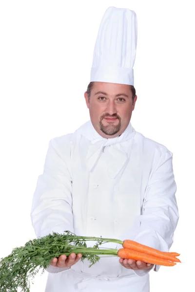 Chef en uniforme avec un tas de carottes fraîches — Photo