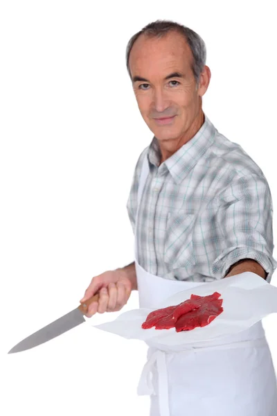 Mature butcher with knife showing steak — Stock Photo, Image