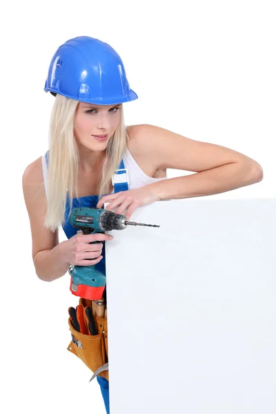 Woman with a power drill and a board left blank for your message — Stock Photo, Image