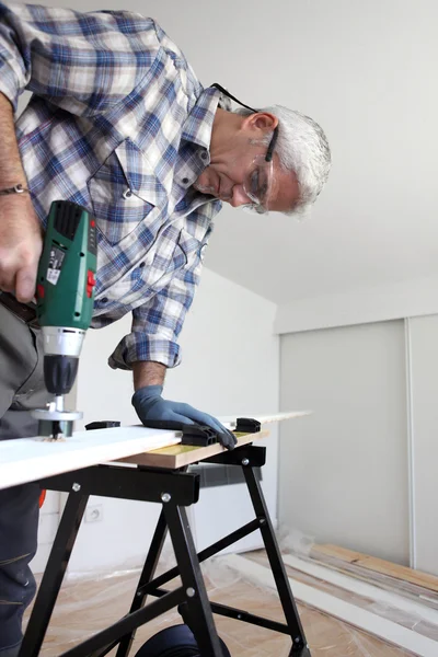 Carpenter protecting eyes with goggles whilst drilling Royalty Free Stock Images