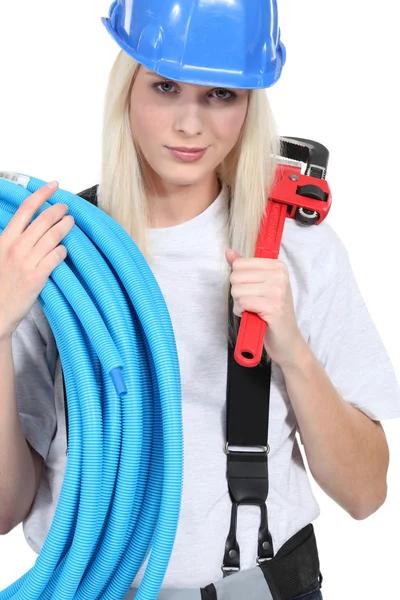 Tradeswoman segurando tubulação ondulada e uma chave de tubo — Fotografia de Stock