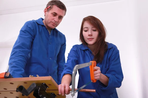 Handwerker und Lehrling schneiden ein Rohr — Stockfoto
