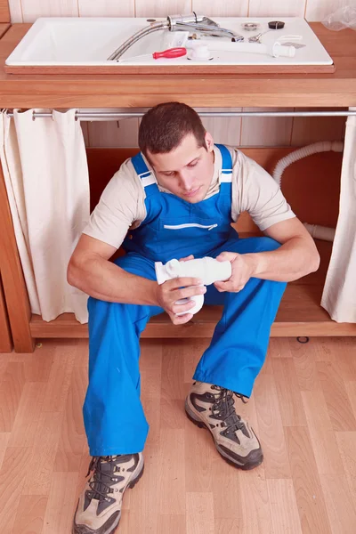 Plumber sitting in front of sink — Stock Photo, Image