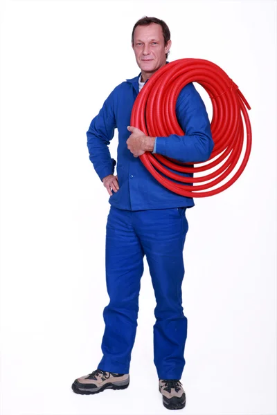 Tradesman holding coiled tubing around his shoulder — Stock Photo, Image