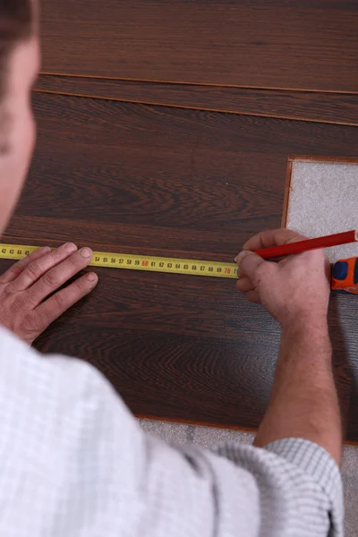 Hombre que mide el listón de parquet — Foto de Stock