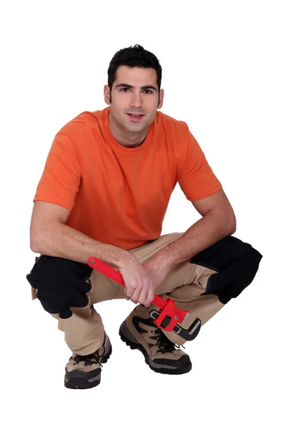 Craftsman crouching spanner in hand — Stok fotoğraf