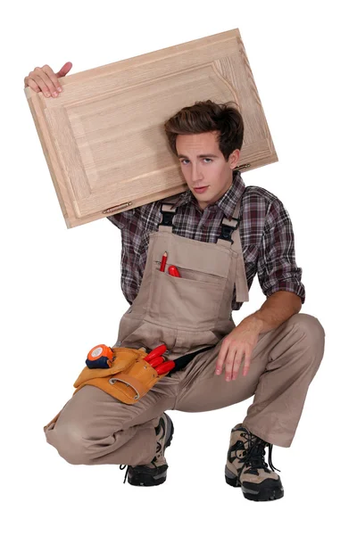 年轻细木工家庭携带碗橱门在肩膀上的肖像 — 图库照片
